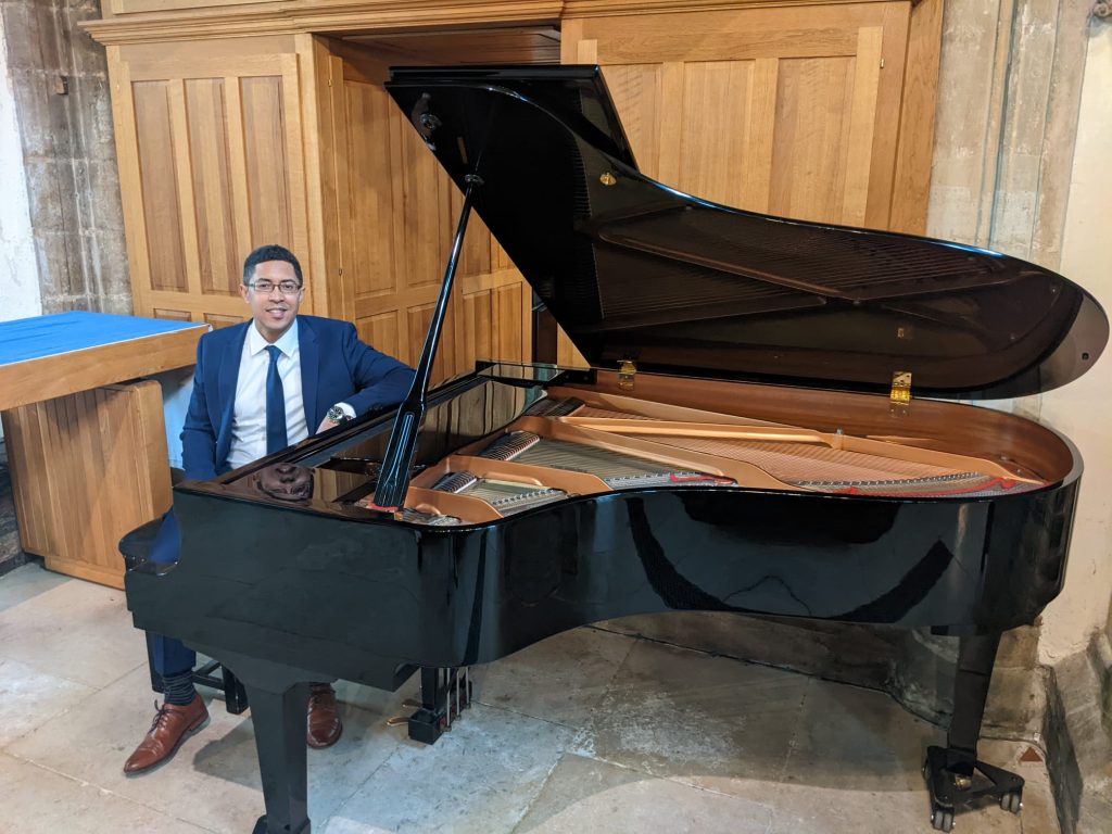 David A T Önaç in suit sitting at a grand piano