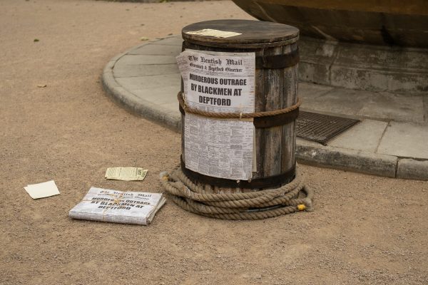 A barrel with newspaper on it, newspaper says: Murderous outrage by blackmen at depftford