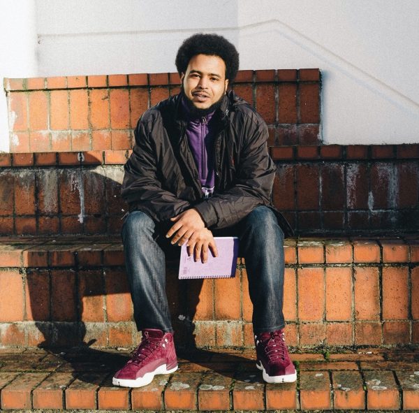 Man with black jacket and jeans sitting on brick stairs
